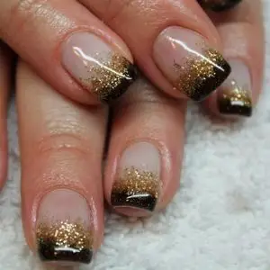 Photo of black french tip nails with gold glitter