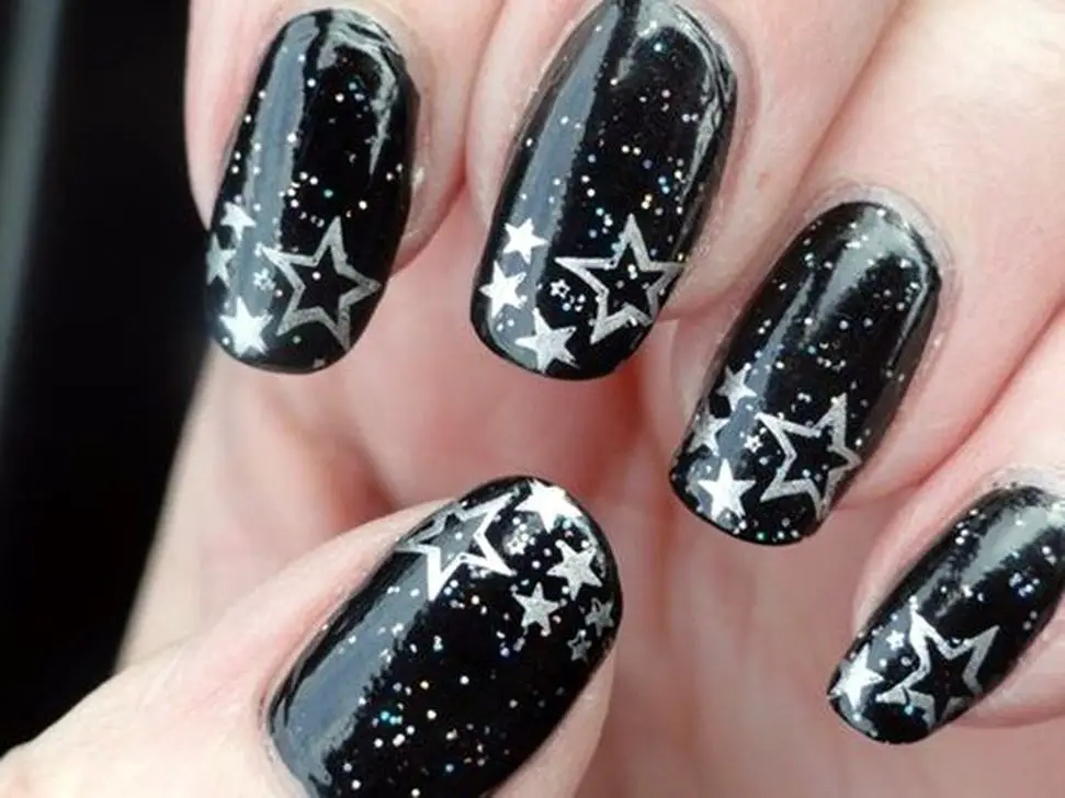Photo of black nails with silver stars and silver glitter