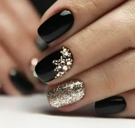 Photo of black and gold nails with glitter